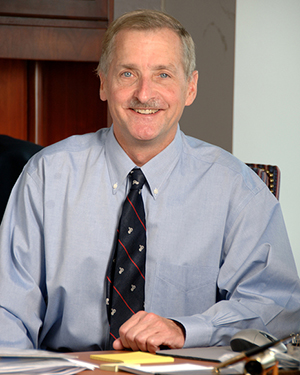 Portrait photo of Dr. Jim Battey at a desk.