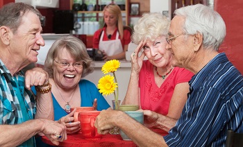 Four older people chat at a table in a cafe.