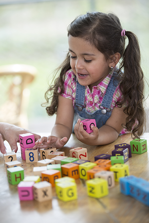 Una niña jugando con letras de colores en bloques.