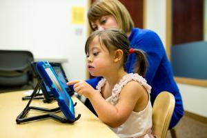 Child with Down syndrome using a tablet.
