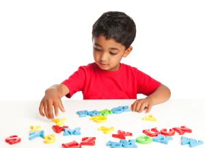 A young boy playing with alphabet letter toys.