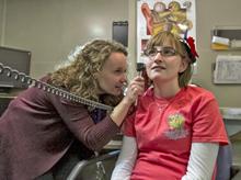 Dr. King performs an otoscopic exam on a clinical trial participant in the audiology clinic.