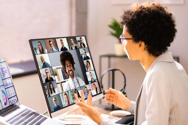 A woman speaking to a group of people on a virtual video call. 