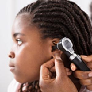 Young girl having her ear checked by a doctor.