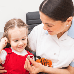Audiologist giving young girl an assistive listening device