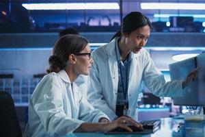 2 researchers reviewing computer screens together.